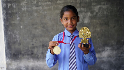 Excited Indian student school child wearing school uniform holding victory trophy in hand, Education concept.