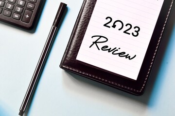 2023 Review note on sky blue background. Recap, assessment, look back and highlights of the year...