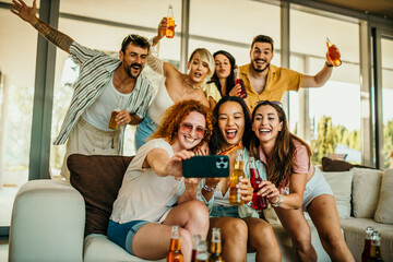 A diverse bunch of buddies having a great time indoors, sharing pizza, drinks, and laughs while snapping photos