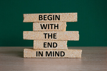 Begin in end of mind symbol. Concept words Begin with the end in mind on brick blocks. Beautiful wooden table green background. Business begin in end of mind concept. Copy space.