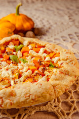 closeup pumpkin pie galette, open pie on beige knitted tablecloth on table. atmospheric evening warm lighting