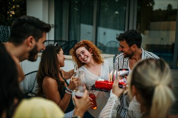 A cheerful group of friends gathers in a sun-drenched backyard, sharing laughter and joy at a lively birthday celebration