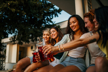 Friends having fun at a backyard party, enjoying the sunset with drinks and snacks.