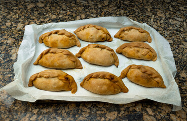 Baked vegetable cocarrois on an aluminum tray and baking paper. Typical empanadas from Mallorca