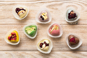chocolate sweets in the form of a heart with fruits and nuts on a colored background. top view with space for text, holiday concept