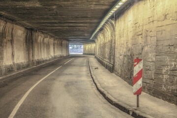 an empty street surrounded by concrete walls in a tunnel,