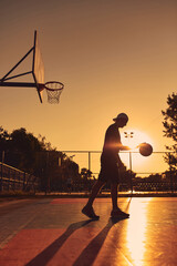 Man playing basketball on a public court in golden hour time.