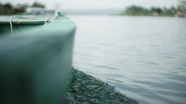 Closeup slow-motion footage of the bow of a wooden boat sailing on Peten Itza lake on a cloudy day