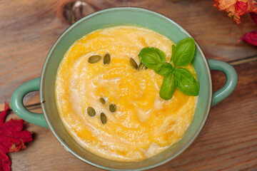A bowl of delicious fall pumpkin soup with pumpkin seeds and basil.