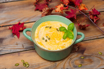 A bowl of delicious fall pumpkin soup with pumpkin seeds and basil.