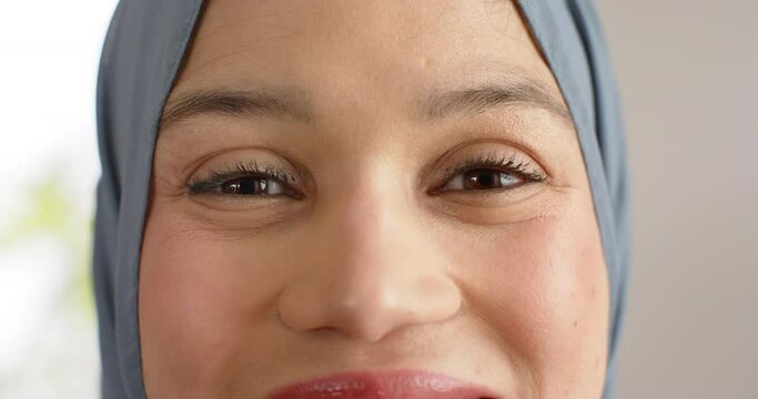 Portrait of smiling biracial woman in hijab with copy space, slow motion