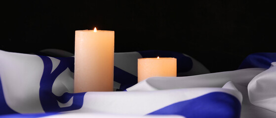 Burning candles and flag of Israel on dark background