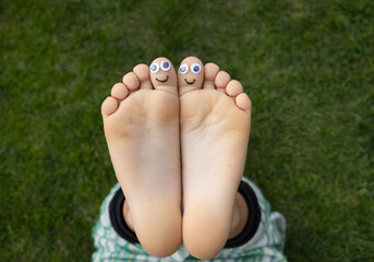 Children's bare feet with painted faces on the big toes. cheerful positive atmosphere, happy...