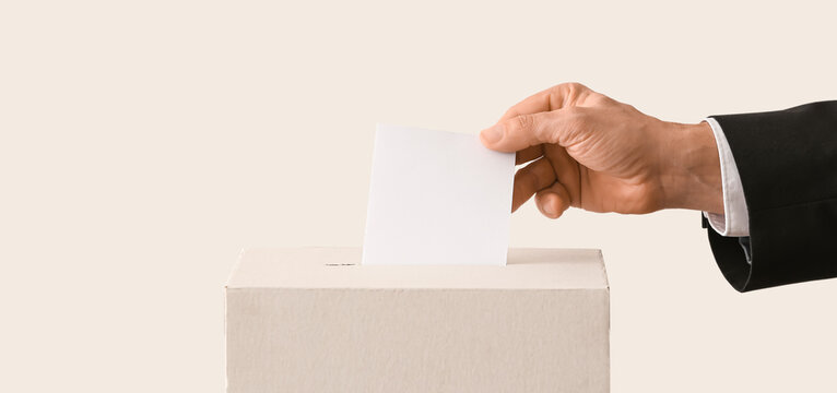Voting man near ballot box on light background with space for text, closeup