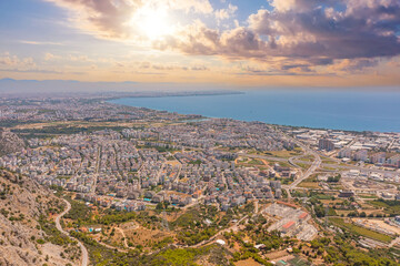 Flight over ridge mountain, bird's eye view sunrise sunset dawn evening morning overlooking the city, houses and buildings, roads and ships, Mediterranean coast, resort area, vacation trip.