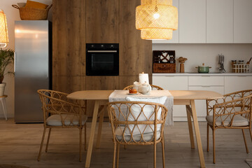 Interior of modern kitchen with glowing lamp and teapot on dining table
