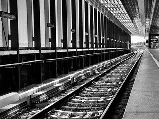 Train station with a single train track stretching out in the distance, in grayscale