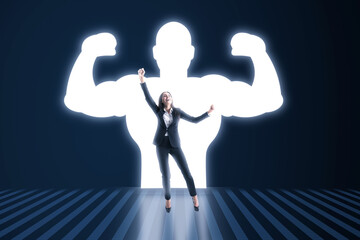 Happy european businesswoman with very strong illuminated shadow flexing muscles on dark wall background. Personal development, inner strength, motivation concept.