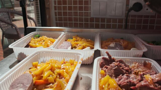 The chef lays out the cooked meat in plastic containers with Uzbek pilaf