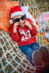 baby in santa claus hat and sunglasses lying on a hammock