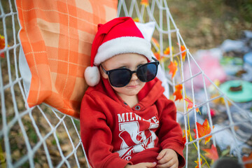baby in santa claus hat and sunglasses lying on a hammock