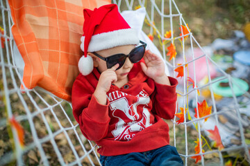 baby in santa claus hat and sunglasses lying on a hammock