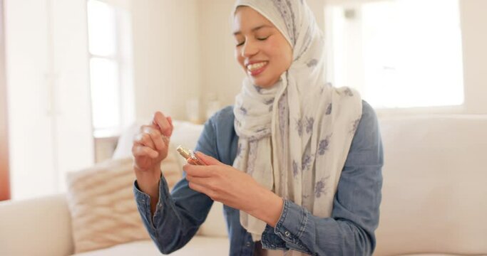 Happy biracial woman in hijab smelling perfume at home, copy space, slow motion