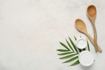 Fototapeta na wymiar Composition with jars of cosmetic products, wooden spoons and palm leaf on light background