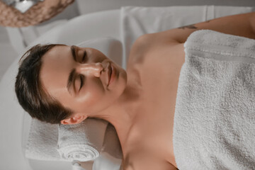 Obraz na płótnie Canvas Young woman relaxing in dark spa salon, closeup
