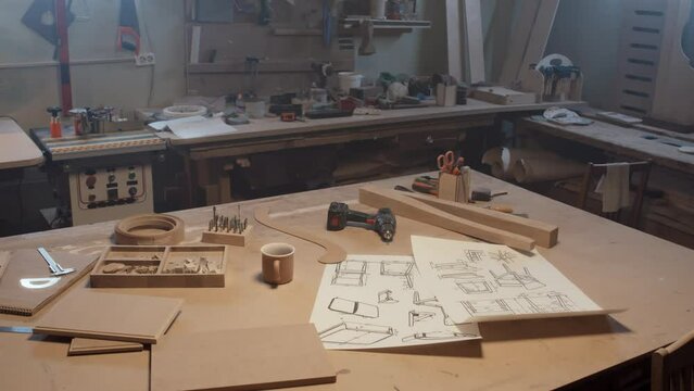 Medium shot of consrtuction drawing of chair and special carpenter equipment on wooden table in workshop