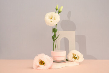 Composition with jar of cosmetic product, plaster podium and beautiful eustoma flowers on beige background