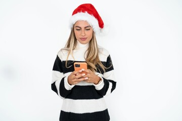 Focused Beautiful hispanic woman wearing christmas hat and striped knitted sweater use smartphone reading social media news, or important e-mail