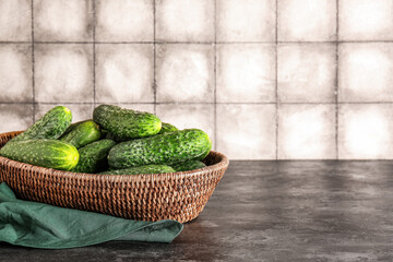 Wicker bowl with fresh cucumbers on table