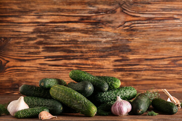 Heap of fresh cucumbers with garlic and dill on wooden background