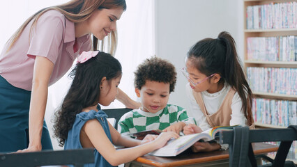 Female teacher helping school kids in classroom. Elementary woman teacher teaching students doing the lesson in classroom. Education knowledge concept
