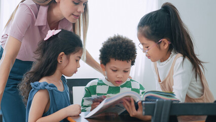 Female teacher helping school kids in classroom. Elementary woman teacher teaching students doing the lesson in classroom. Education knowledge concept