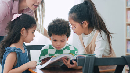 Female teacher helping school kids in classroom. Elementary woman teacher teaching students doing the lesson in classroom. Education knowledge concept