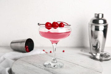 Glass of Cosmopolitan cocktail with cherries on white background