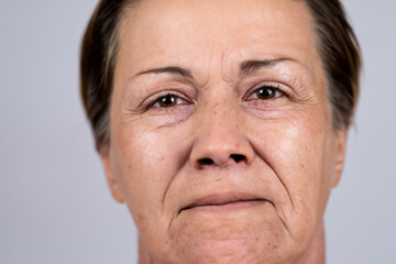 dark-haired mature woman examines her wrinkles on her face near the mirror. AI GENERATE
