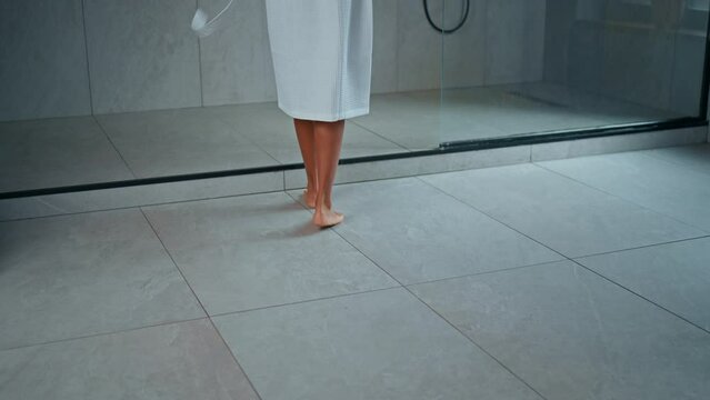 back view woman dressed white bathrobe walks to the shower cabin slow motion bathroom at home morning routine