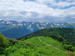 Snow-Capped Mountains with Green and Dry Grass, Clouds, and a Stunning Sky