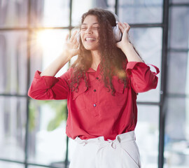 Fototapeta premium Beautiful smiling young woman in headphones in modern office