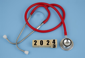 Changes in health care in year 2024. Red stethoscope and numbers 2023 and 2024 on wooden cubes on...