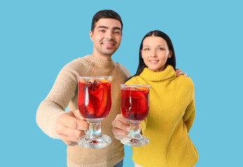 Young couple with glasses of mulled wine on blue background