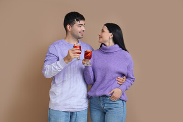 Young couple with glasses of mulled wine on color background