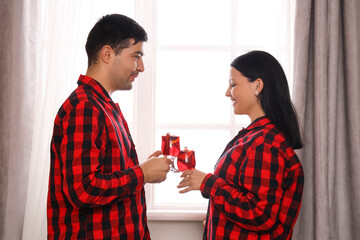 Young couple with glasses of mulled wine at home on Christmas eve