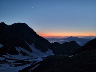 Snow-Capped Mountains with Green and Dry Grass, Clouds, and a Stunning Sky
