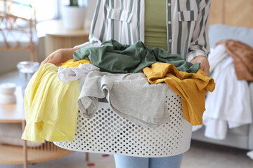 Young woman with basket full of dirty clothes at home, closeup