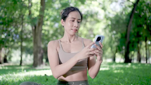 Asian woman using mobile phone online in public forest