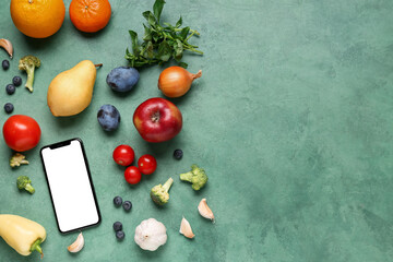 Mobile phone with fresh vegetables and fruits on green background. World Vegan Day concept - obrazy, fototapety, plakaty